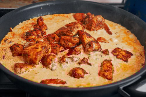 Seared chicken pieces simmering in a creamy onion sauce