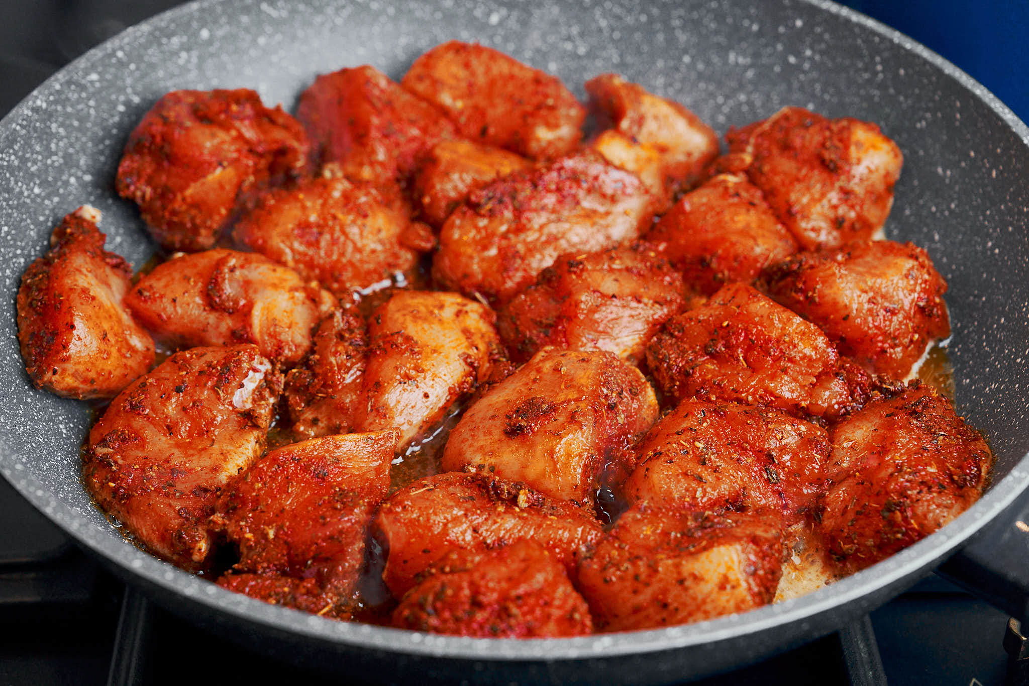 Chicken pieces searing in a skillet until golden