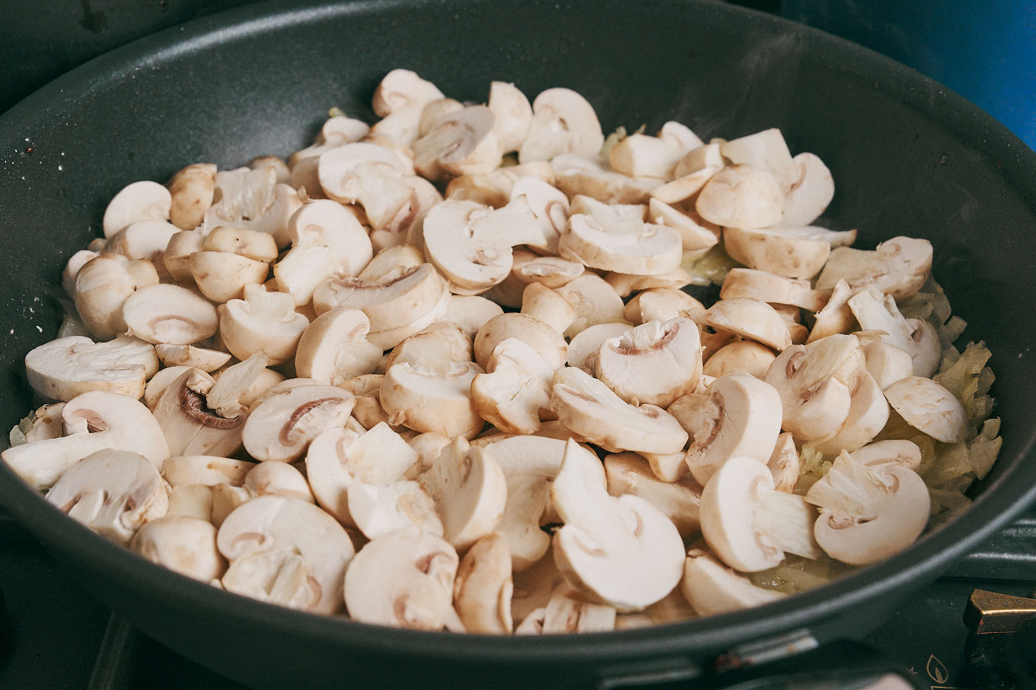 sliced mushrooms added to the skillet over sautéed onions