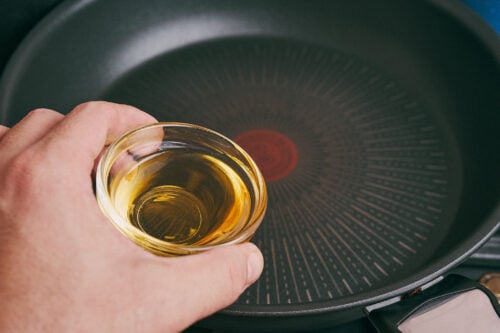olive oil being poured into a skillet to start cooking ground beef