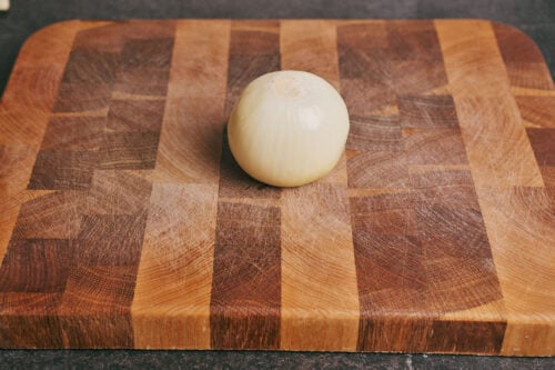 whole onion on a wooden cutting board