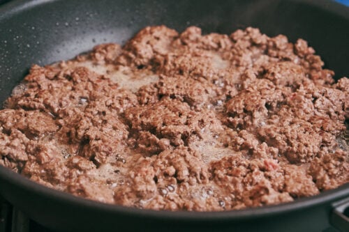 ground beef browning in a skillet as it cooks evenly