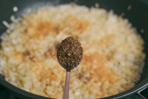 Adding thyme to onions while cooking