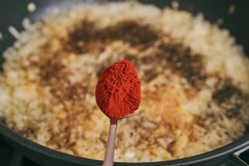 Adding smoked paprika to onions in a skillet