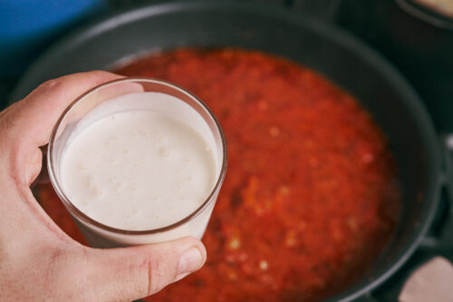 Pouring cream into tomato beef sauce