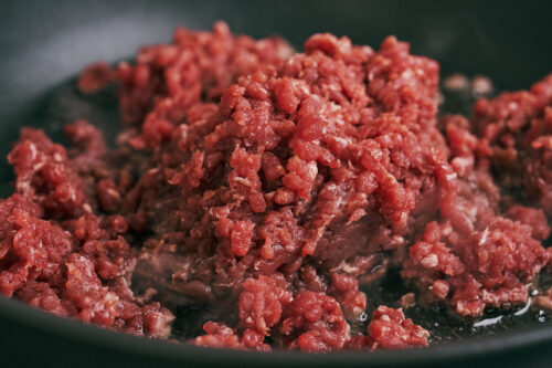 Ground beef cooking in a skillet as it begins to brown