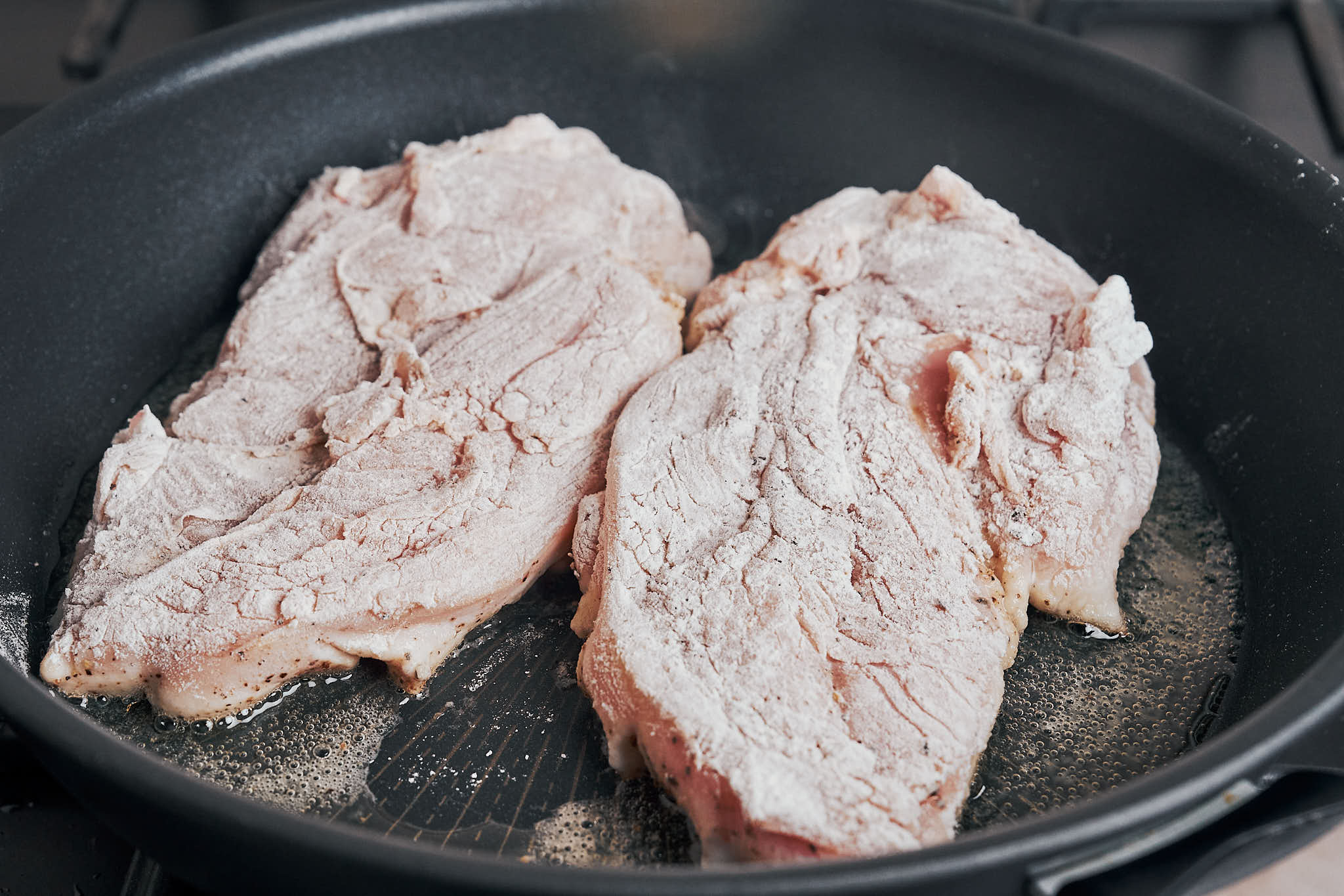 Floured chicken searing in a skillet over medium-high heat