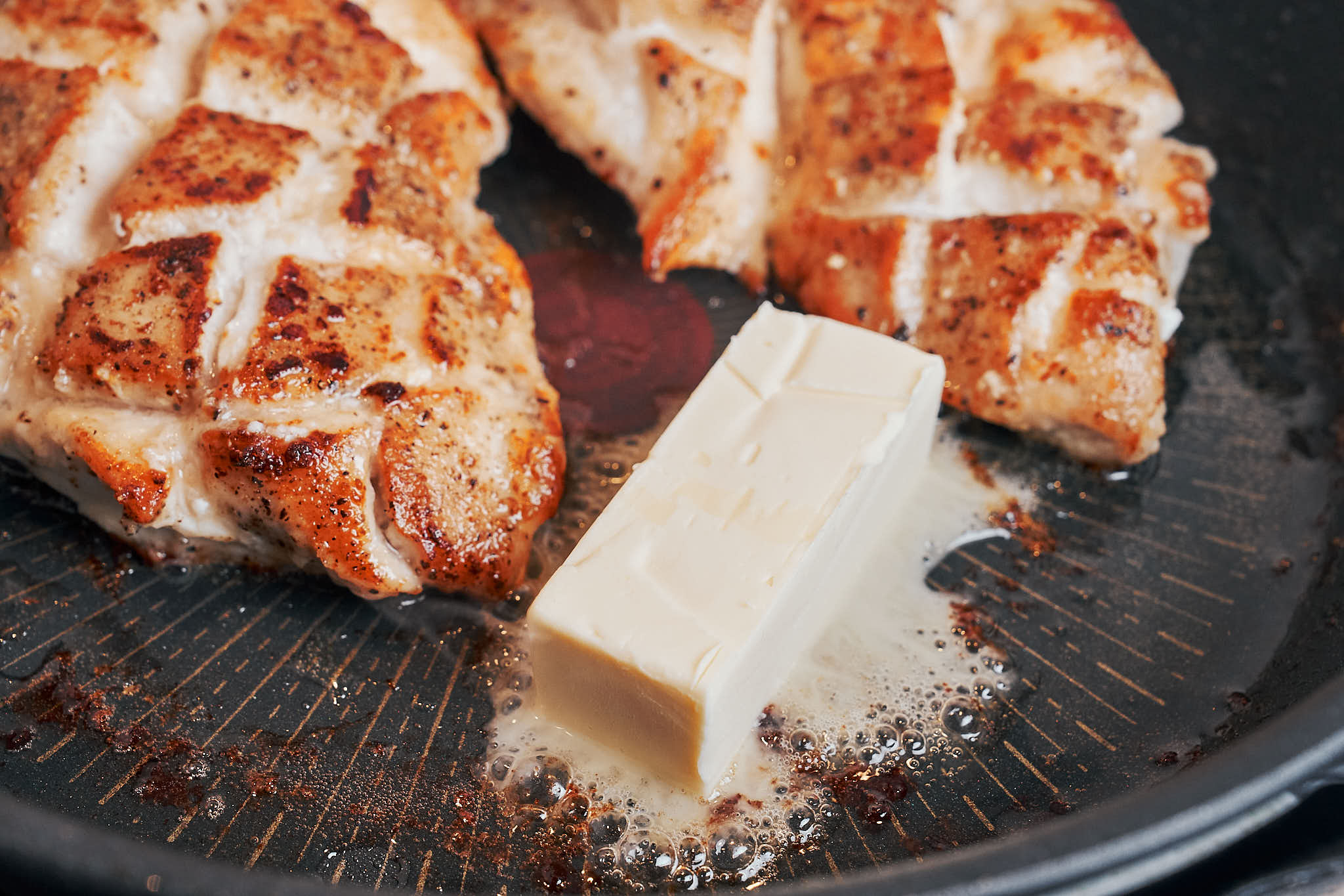 Butter melting in a skillet with seared chicken