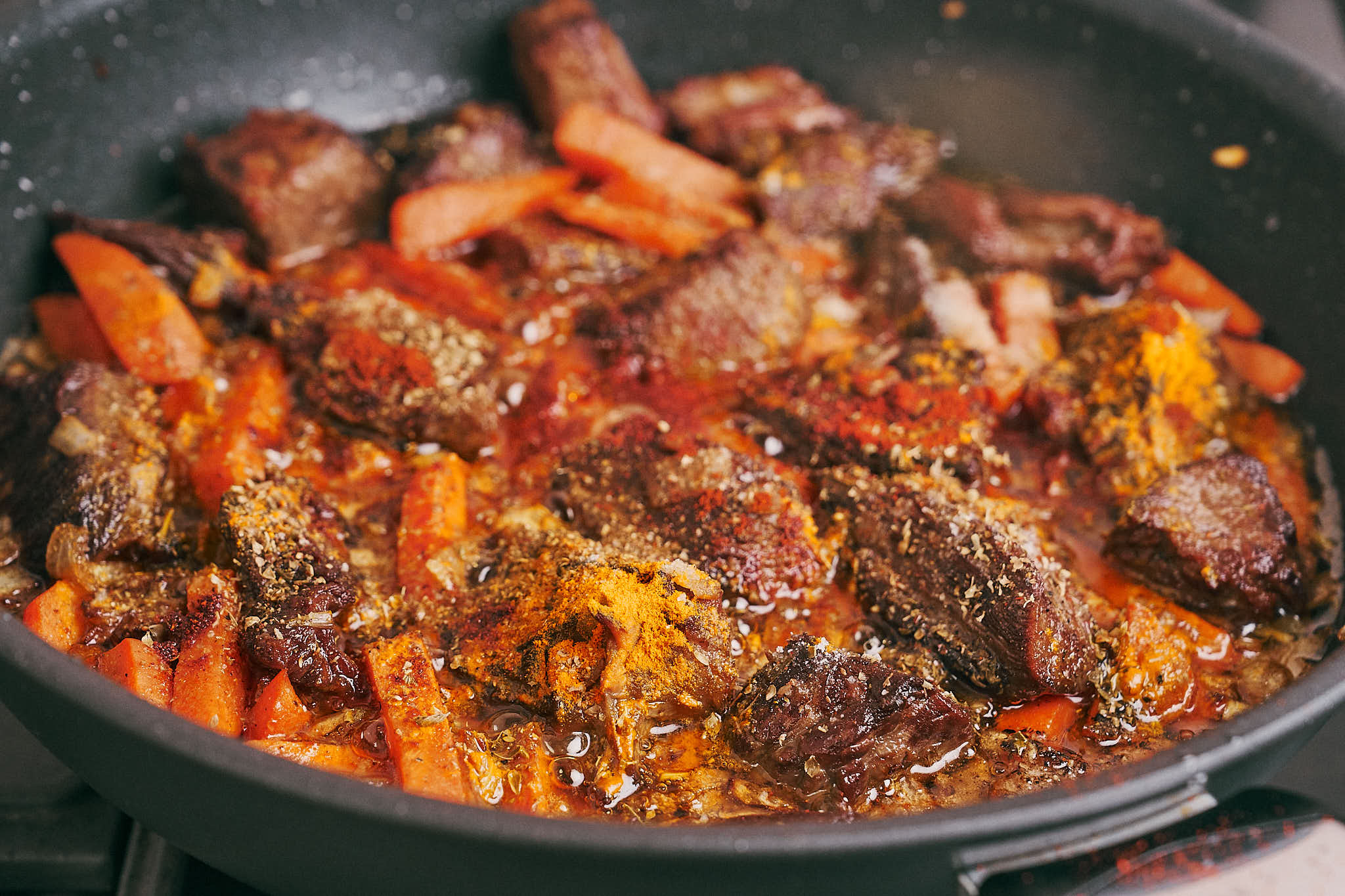 Spices added to beef, onion, and carrot in skillet