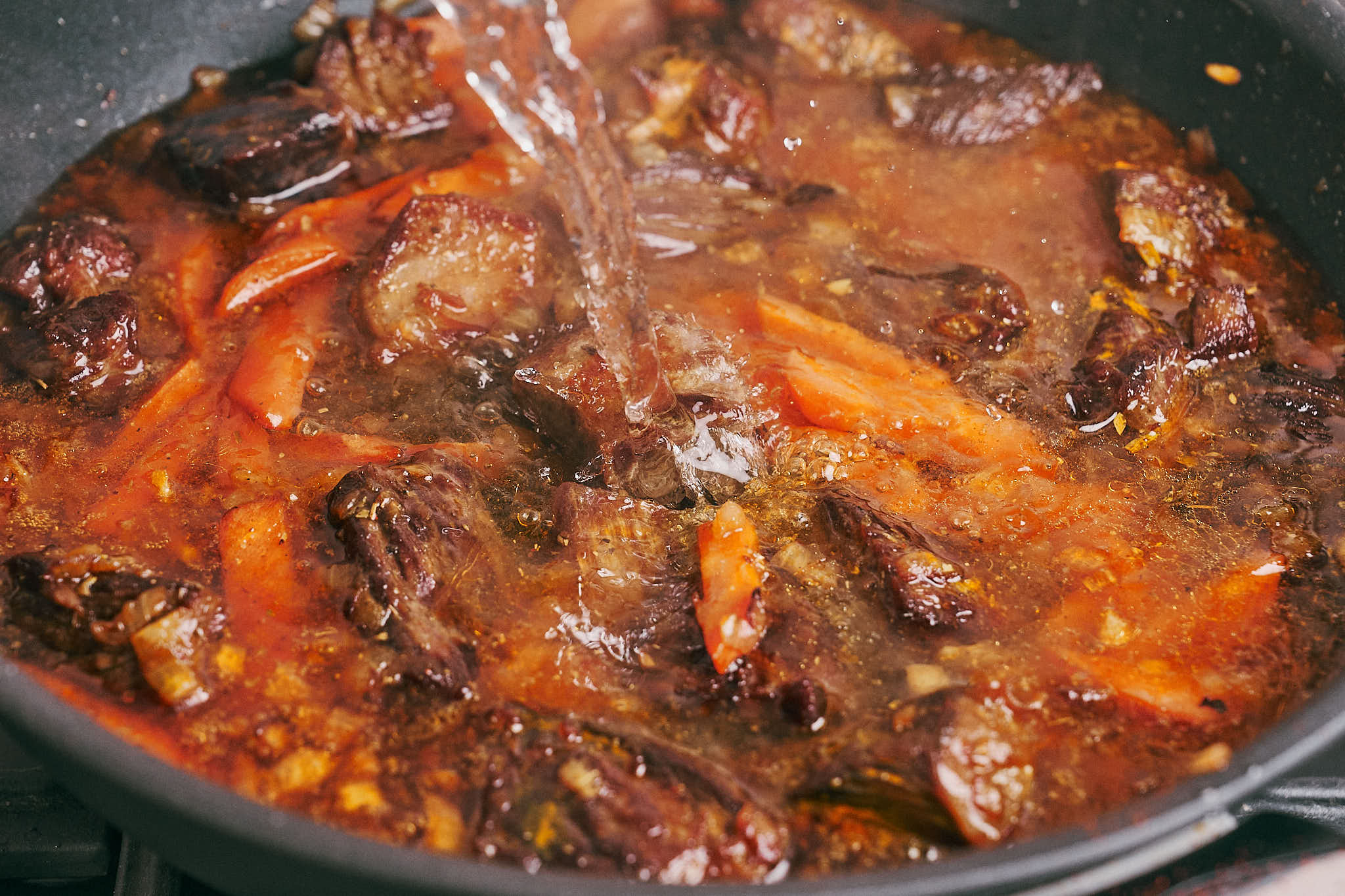 Boiling water poured into skillet to braise beef