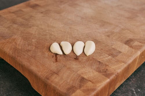 Garlic cloves cut in half on cutting board