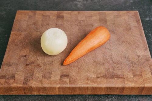 Whole onion and carrot on cutting board