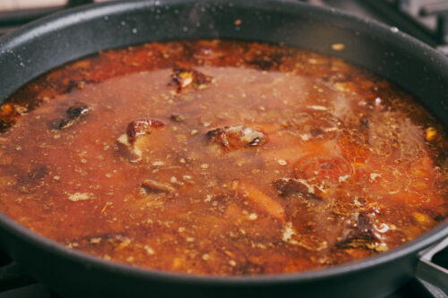 Beef simmering in skillet with spices and broth