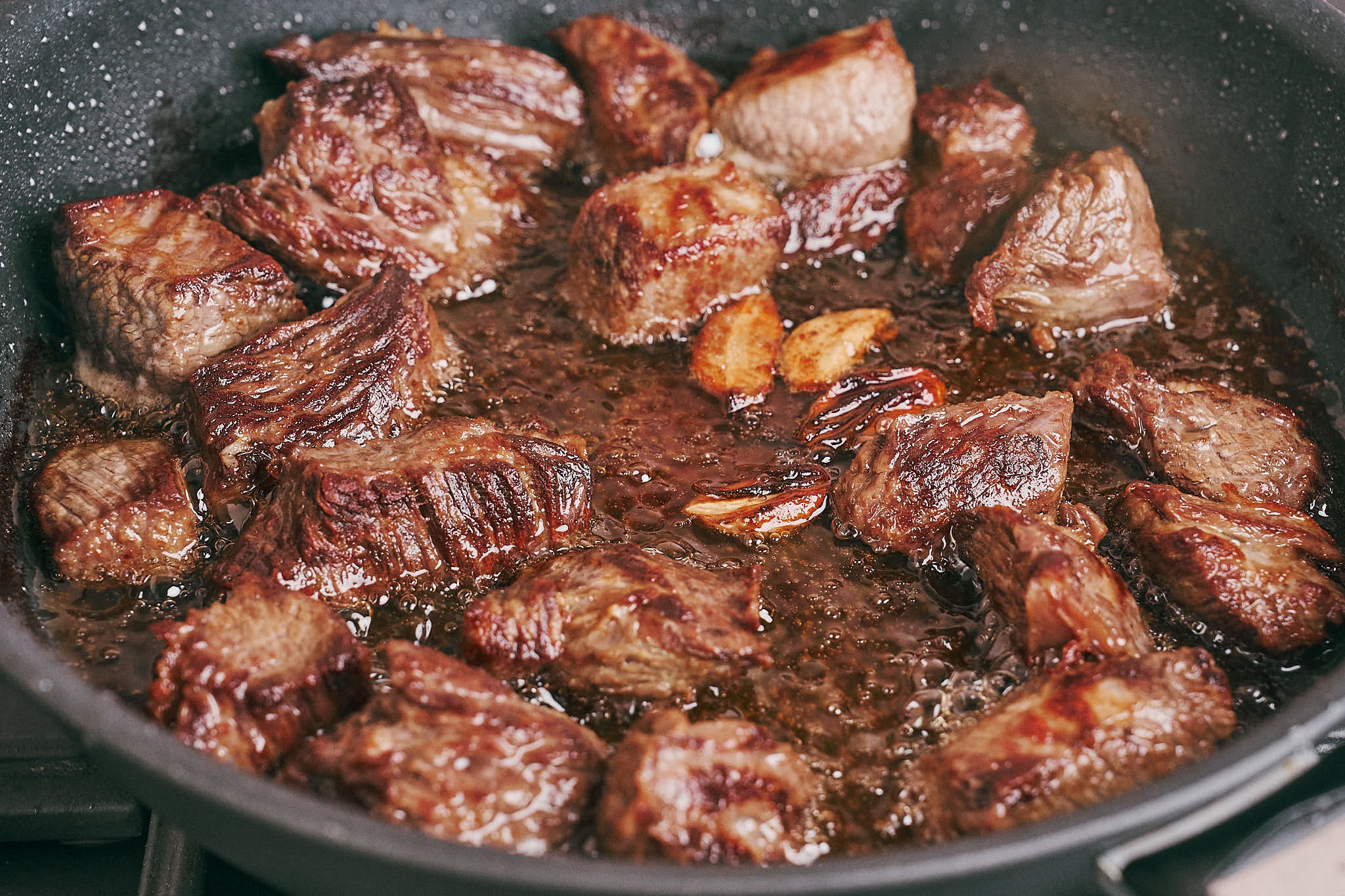 Beef browned in skillet with garlic and oil