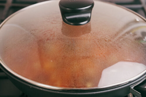 Skillet covered with lid while beef simmers