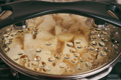 Stewed potatoes and pork simmering covered in a pot