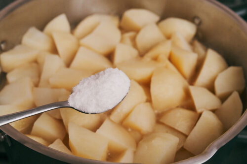 Salt added to potatoes and pork during simmering
