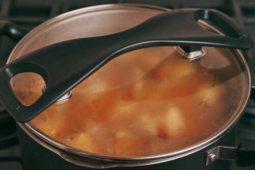 Stewed potatoes and pork simmering covered in a pot