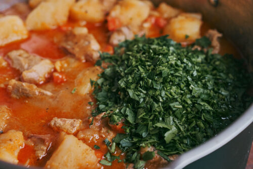 Fresh parsley added to stewed potatoes and pork