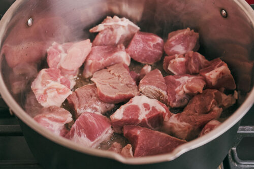 Cubed pork shoulder added to the pot for browning