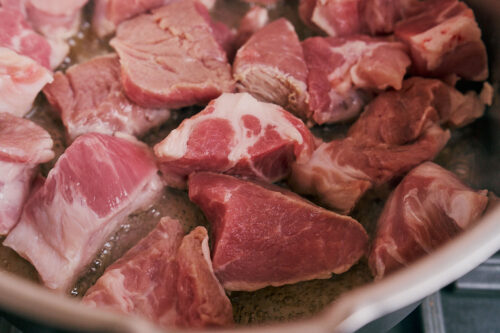 Pork shoulder browning in olive oil over medium-high heat