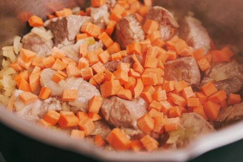 Diced carrots added to pork and onions
