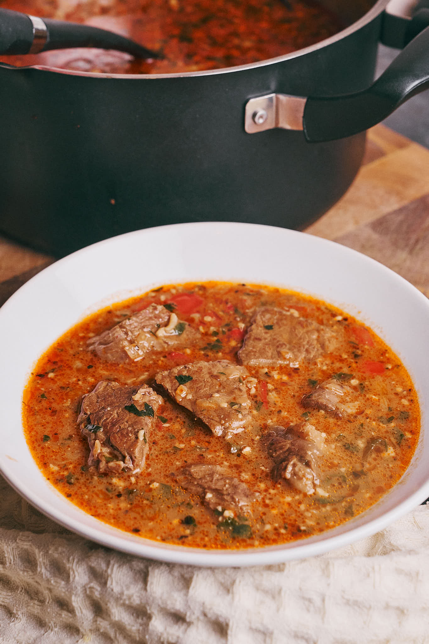 Hearty beef soup with walnuts, rice, and pomegranate broth served in a white bowl