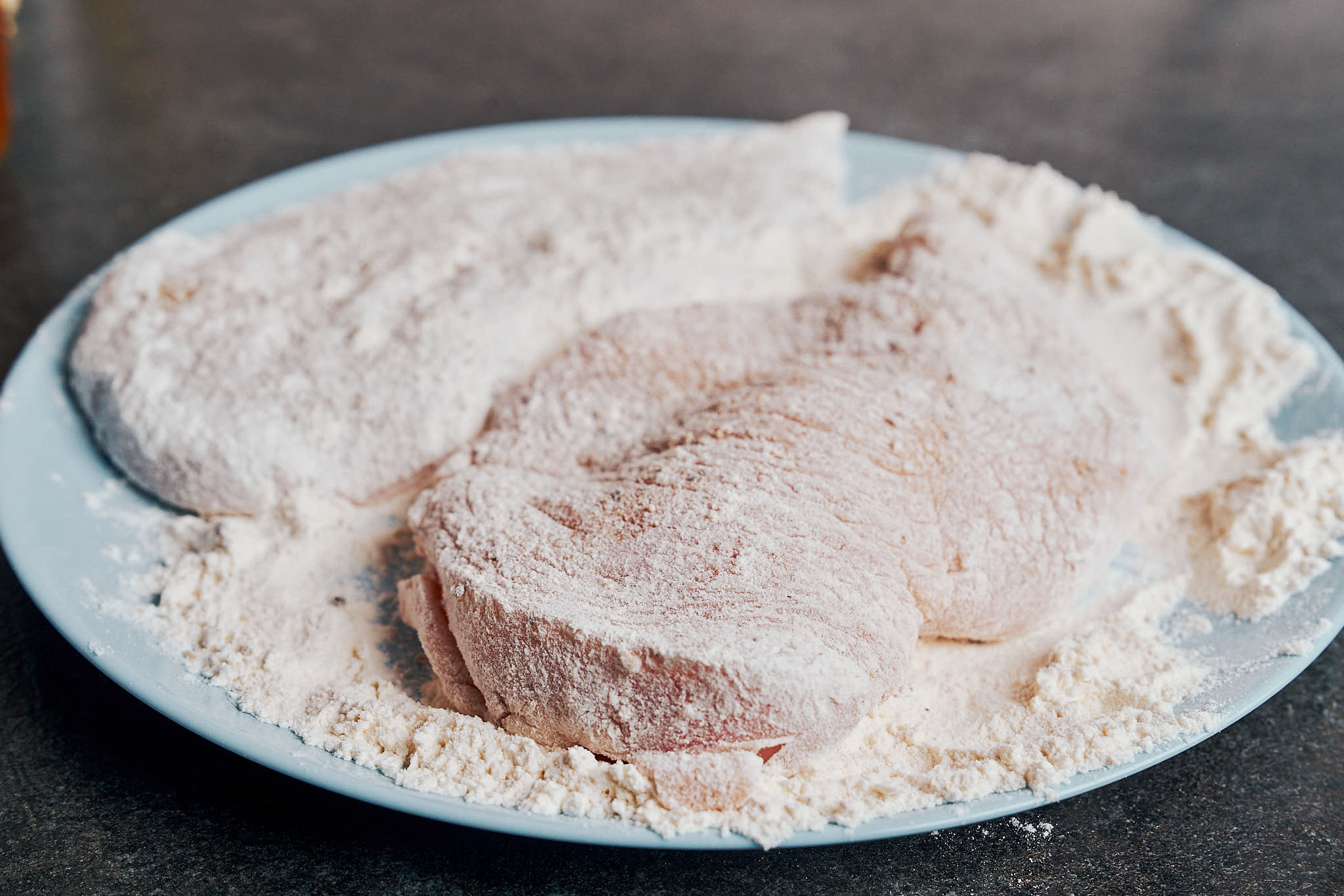 Chicken breasts lightly coated in flour on a plate