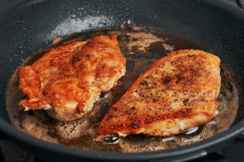 Chicken breasts seared until golden in a skillet