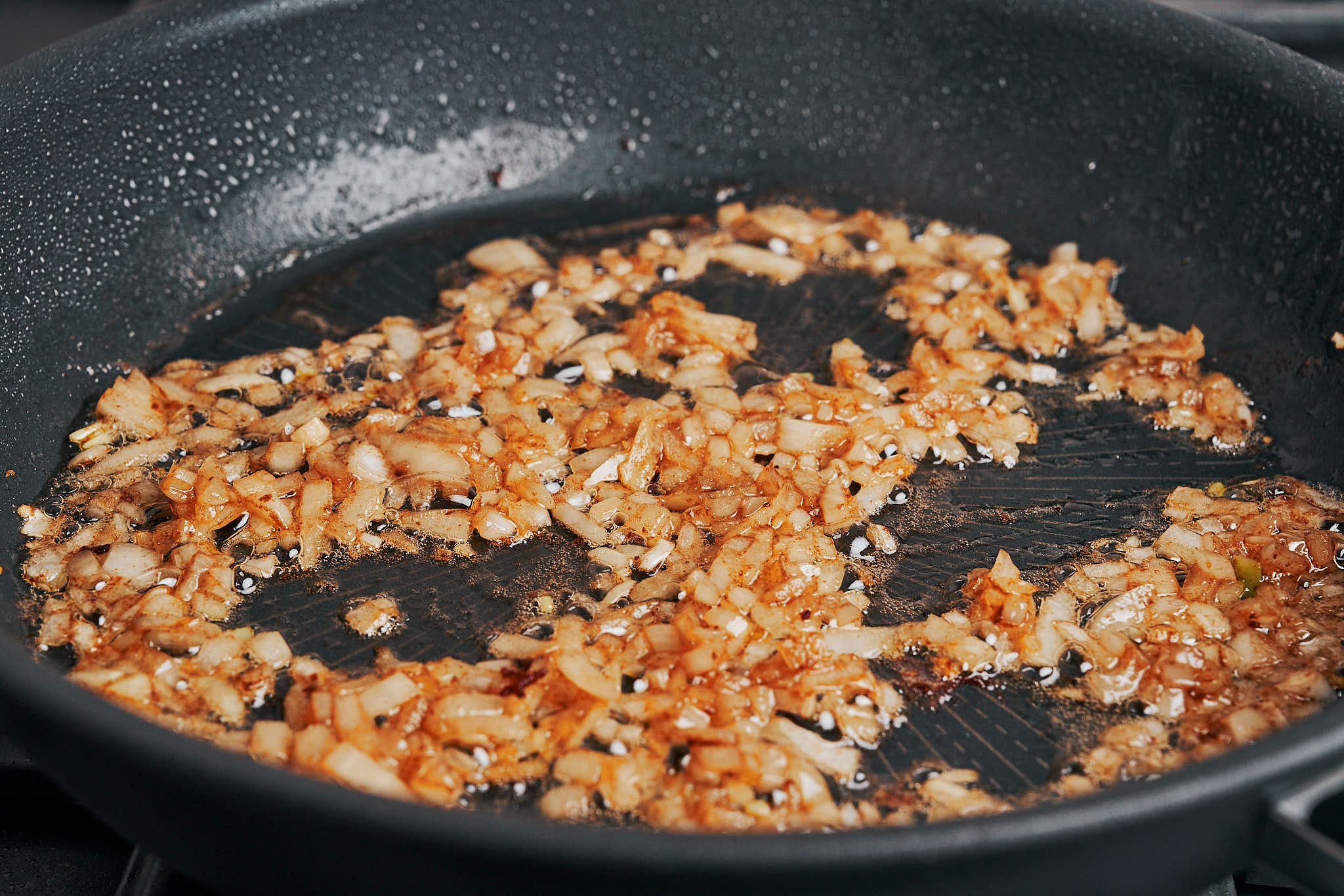 Onion cooking in a skillet until soft and lightly golden