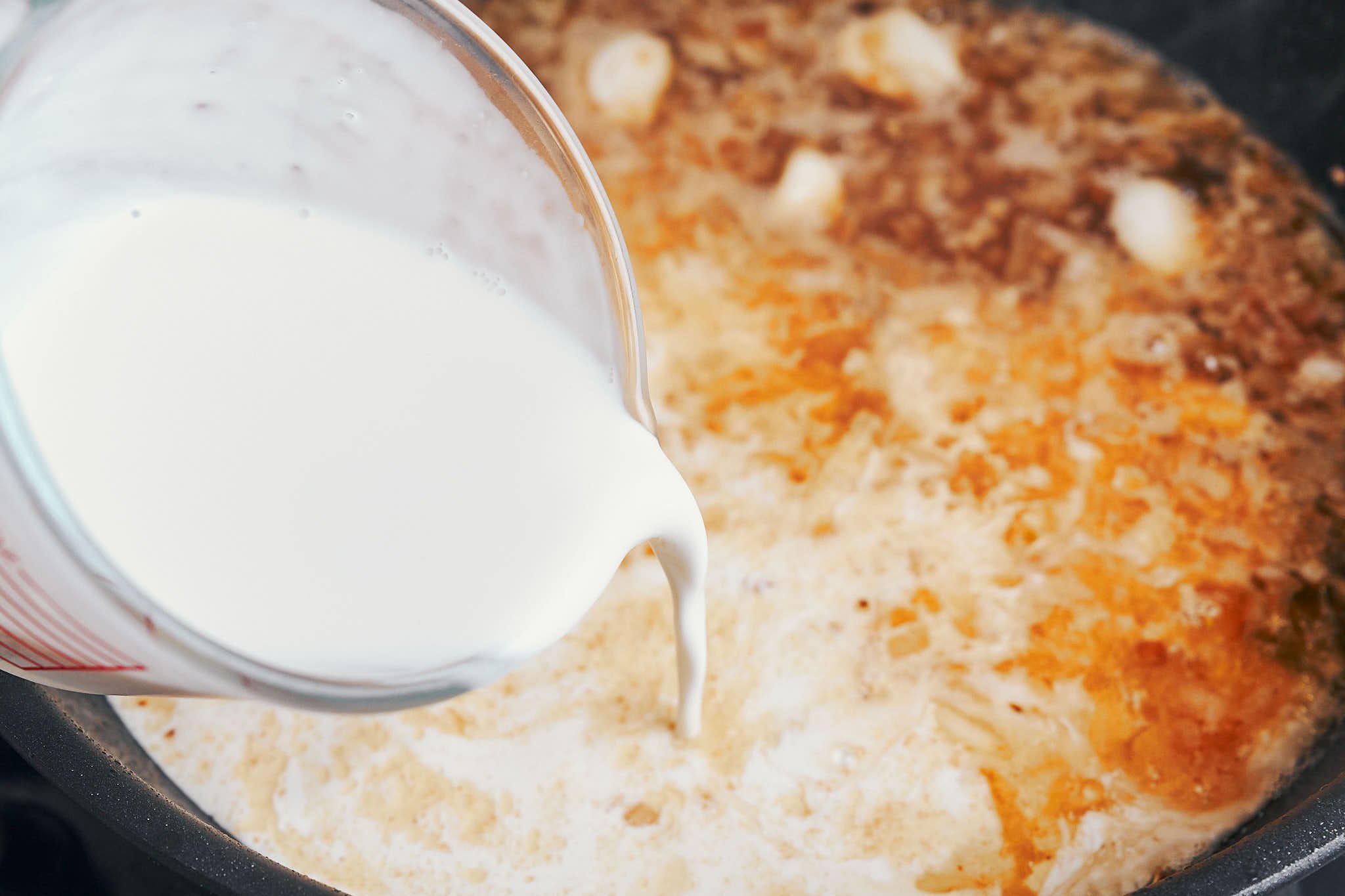 Cream being poured into the skillet to finish the sauce
