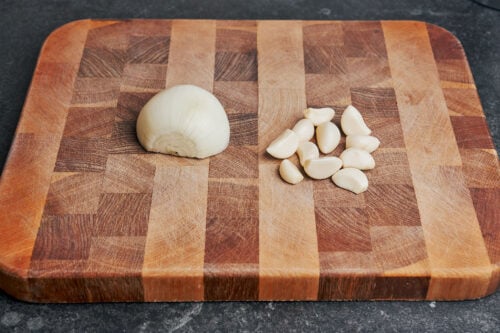 Half an onion and peeled garlic cloves on a cutting board
