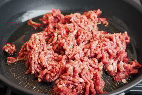 Ground beef added to a skillet before browning