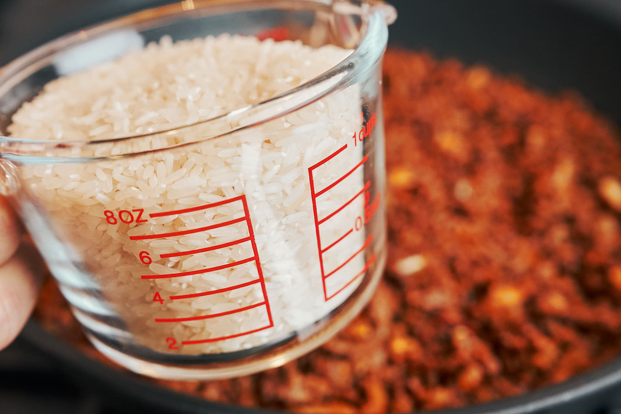 Adding long-grain white rice to ground beef in a skillet