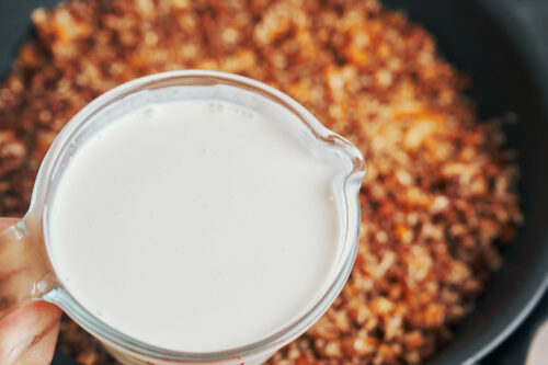 Pouring milk into ground beef and rice mixture