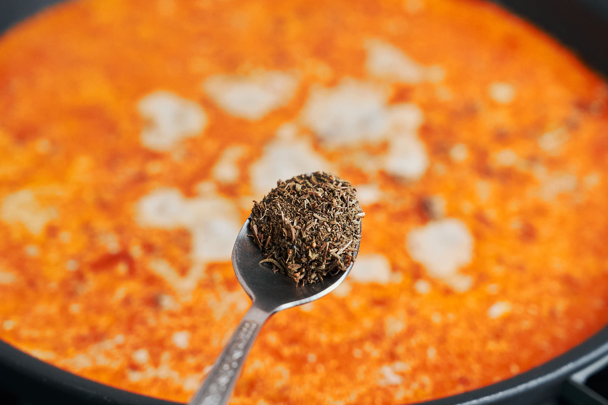 Adding dried thyme to creamy ground beef and rice in a skillet