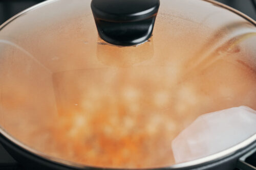 Ground beef and rice cooking covered in a skillet