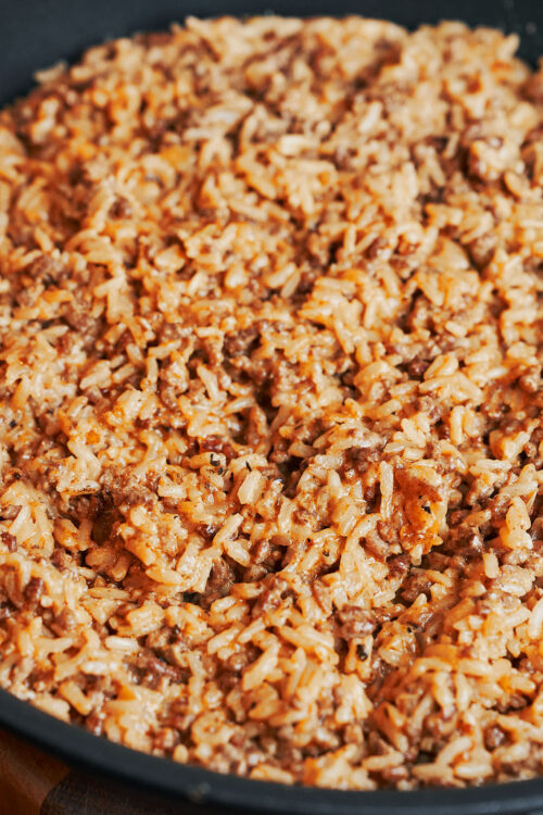 Cooked ground beef and rice with creamy texture in a skillet