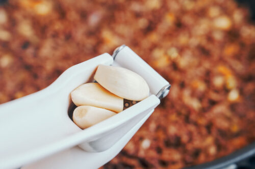 Adding minced garlic to ground beef in a skillet