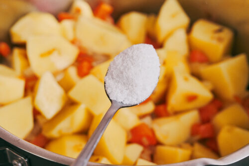 adding salt to potatoes and vegetables in a pot