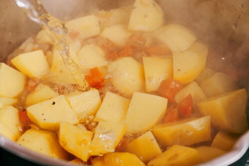 pouring water over potatoes and vegetables