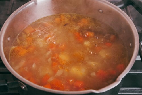 potatoes, onion, and carrot simmering in a pot