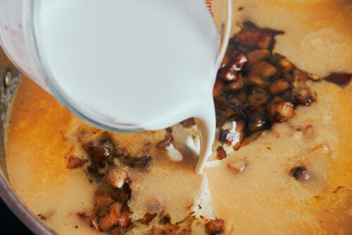pouring heavy cream into mushroom potato soup