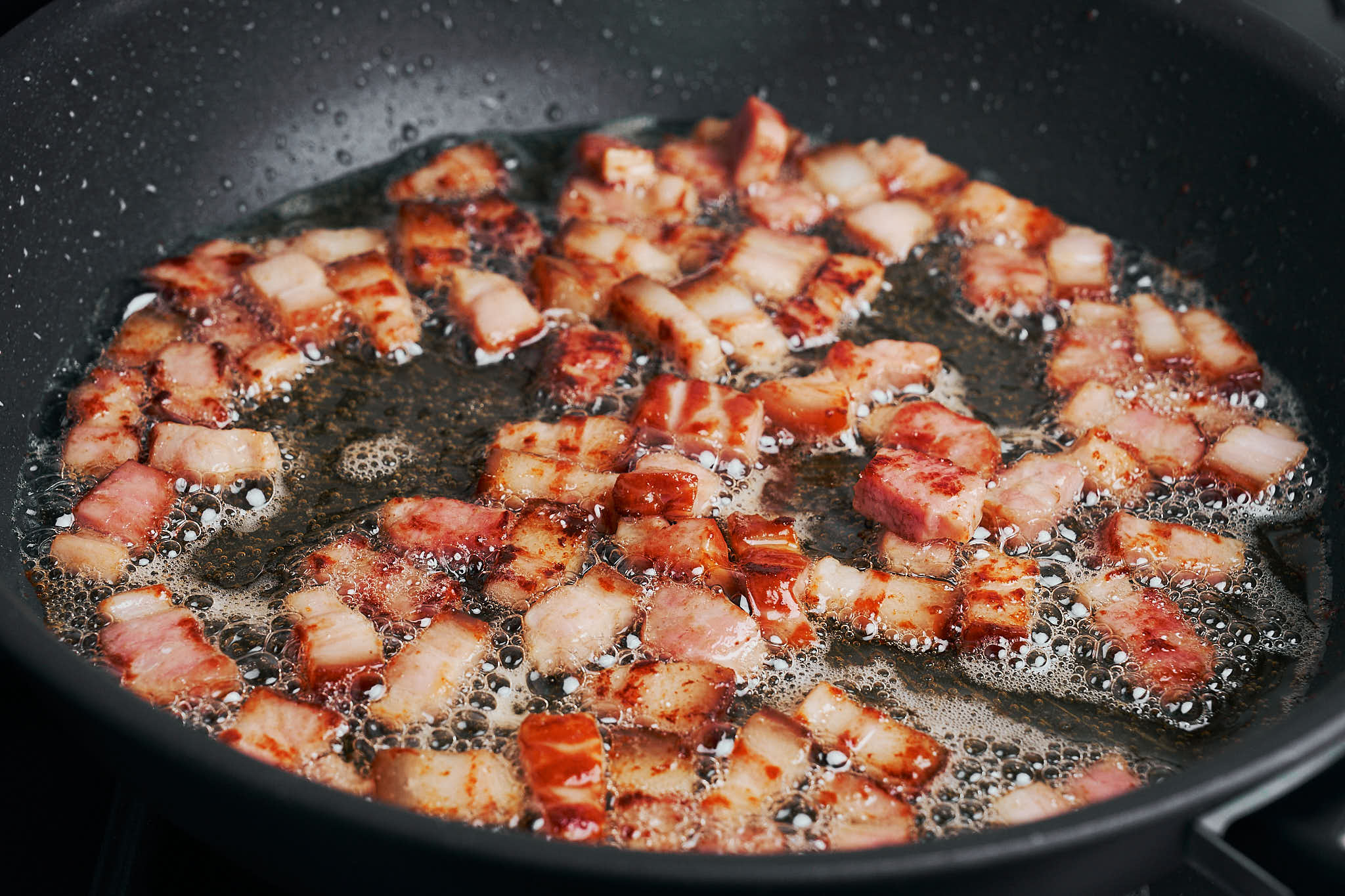 bacon cooking until golden and crisp in a skillet