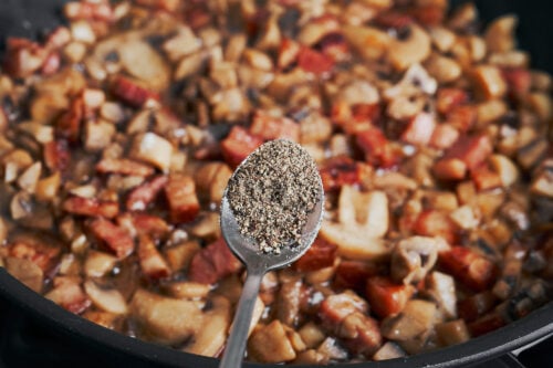 adding black pepper to mushrooms and bacon