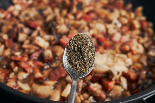 adding dried parsley to mushrooms and bacon
