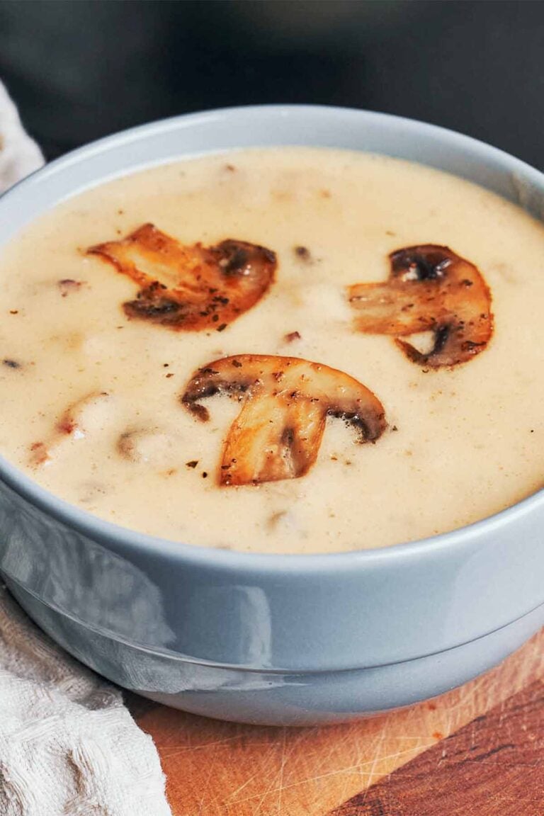 Creamy mushroom soup topped with sautéed mushroom slices in a blue bowl