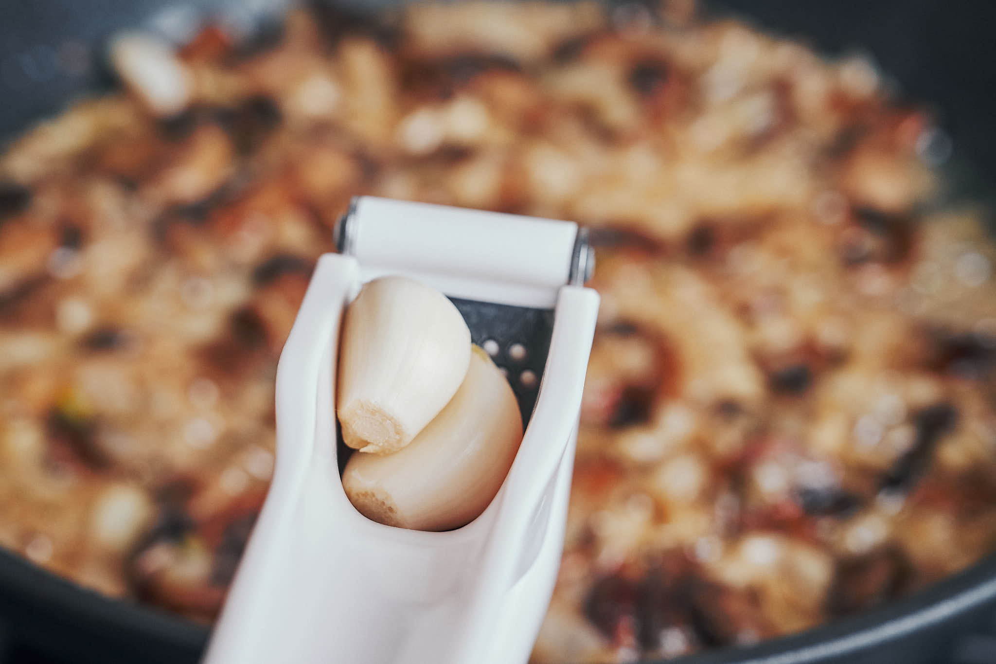adding fresh garlic to mushrooms in a skillet
