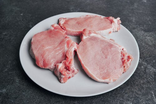 raw pork chops on a plate