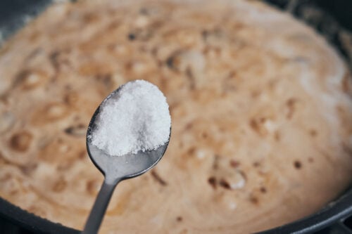 adding salt to creamy mushroom sauce